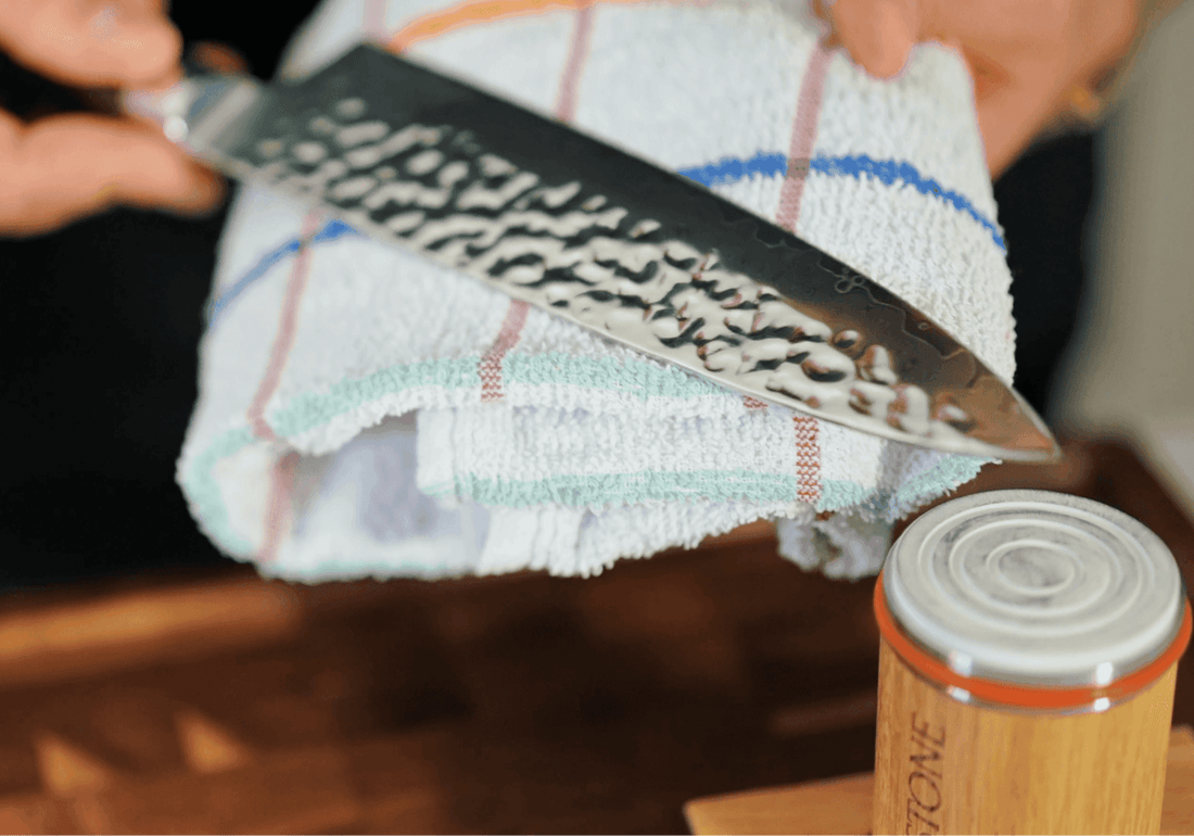 Hand holding a hammered steel knife over a white towel