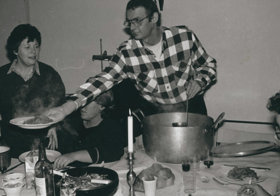 Two people serving food and wine at a set table