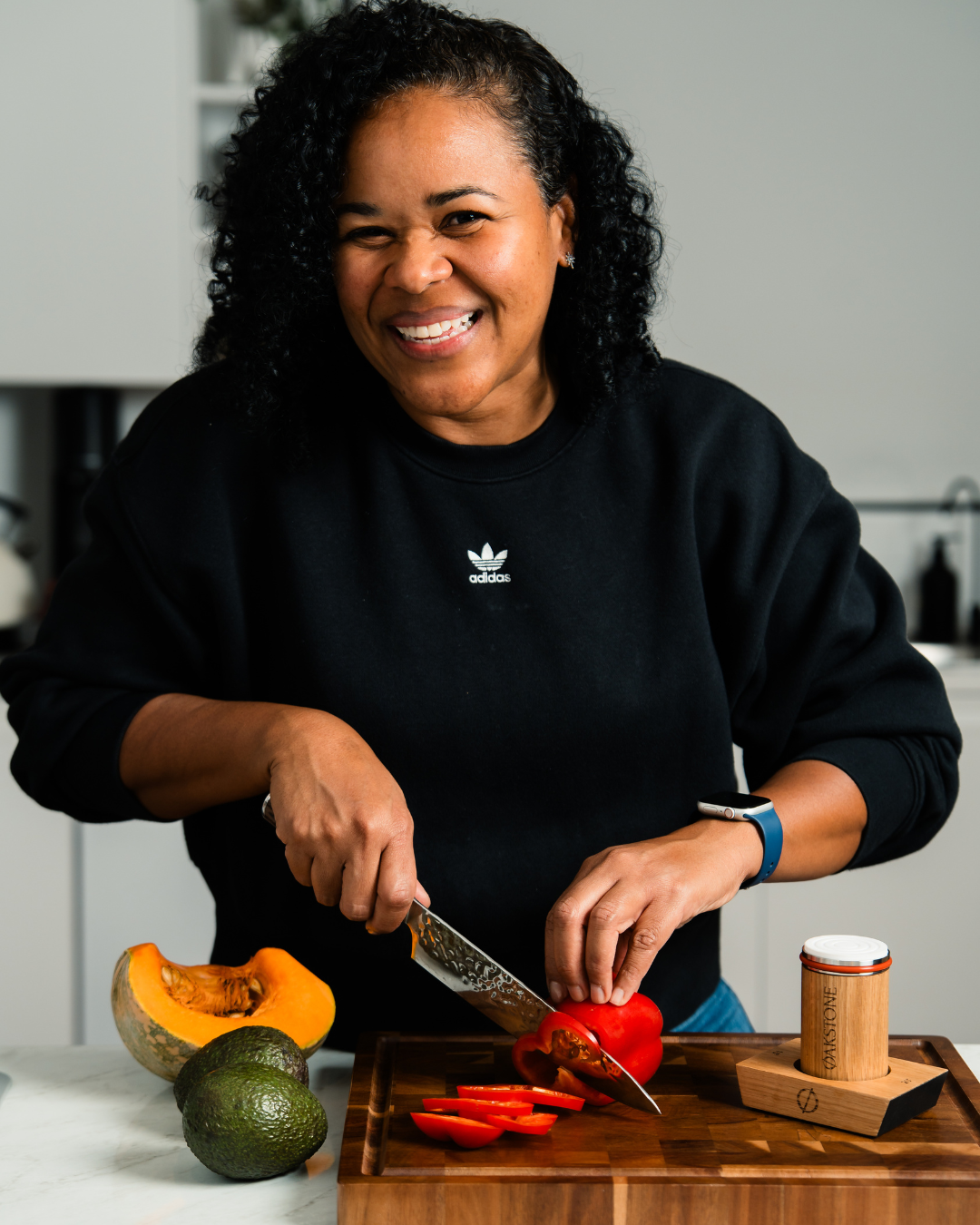 Woman slicing a red pepper in a kitchen with Oakstone packaging nearby