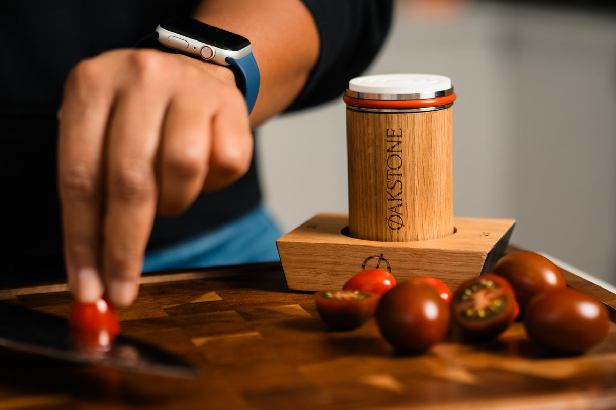Oakstone sharpener sitting in its oak base on a kitchen bench beside fresh tomatoes