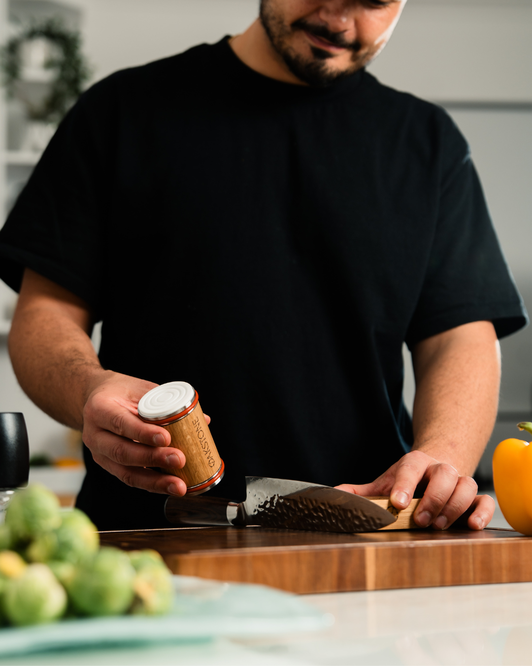 Man in a black t-shirt rolling the Oakstone sharpener along a knife